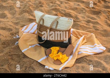 Stylish beach bag, towel and female shoes on sand Stock Photo