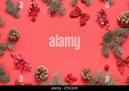 Frame made of fir branches, cones and Christmas decorations on red background Stock Photo