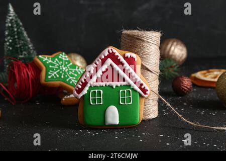 Tasty Christmas cookie in shape of house and decor on table against black grunge background Stock Photo