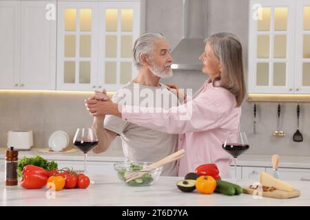 Happy affectionate senior couple dancing in kitchen Stock Photo