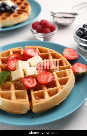 Tasty Belgian waffles with fresh berries served on white table, closeup Stock Photo