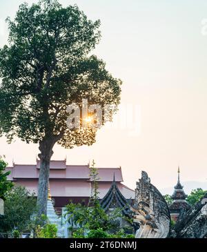 Surrounding the central chedi of the extensive temple area, ancient Lanna architecture,lit by soft setting sunlight, surrounded by trees,within the Ol Stock Photo