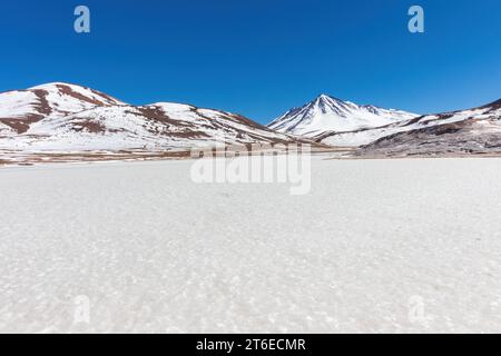 The solid ice of the frozen lake, Laguna Miscanti, during winter in the Andes in northern Chile. Mountains overlook the lagoon. Stock Photo