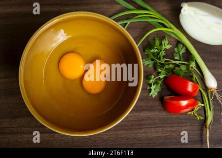 Fresh natural eggs in a bowl with spring onions and coriander to prepare for fried eggs, Omelettes, Egg yolk, Traditional dishes of rural people in Th Stock Photo