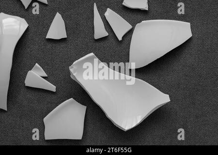 Splinters and Fragments of the broken white ware. Broken Plate, glass.  Pieces of shattered dishes. close-up, top view Stock Photo