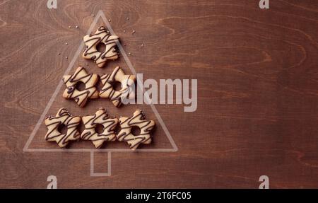 Christmas tree form made from star-shaped cookies with chocolate, banner on the brown wooden background with copy space Stock Photo