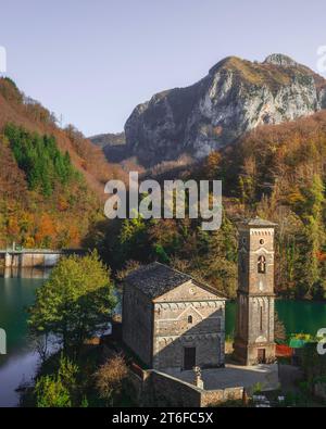 Isola Santa village, church, dam and lake in autumn. Apuan Alps in the background. Garfagnana, Tuscany region, Italy. Stock Photo