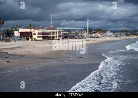 Santa Cruz, USA - 05,02,2023: amusement park located next to sandy beach near waving sea under cloudy stormy sky Stock Photo