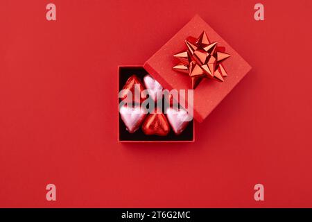 Heart shaped chocolate candies in red gift box on the red background  Stock Photo