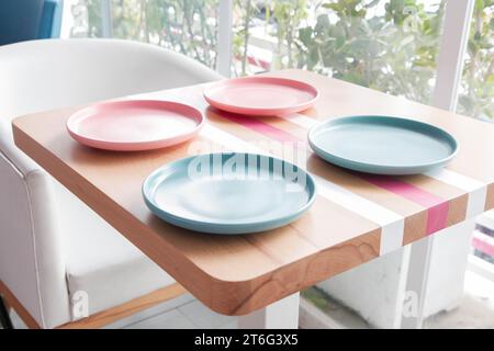 Colourful empty plates on a wooden table at a coffee shop. Stock Photo