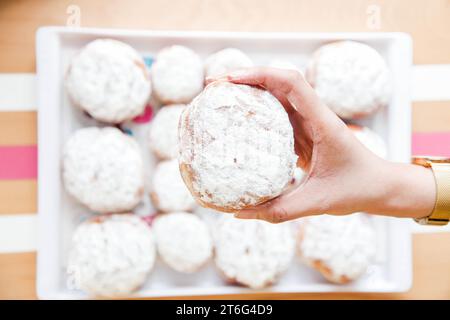 Indulging in Homemade Sweetness: Hands Holding Freshly Baked Dessert Doughnut with Icing and Frosting in a coffee shop. Stock Photo