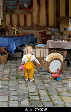 Child with an old fashioned wooden toy at a Flea Market, Brocante, Place Sainte Catherine, Honfleur, Normandy, France Stock Photo