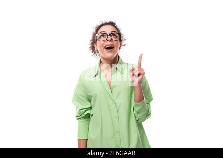 young smart inspired european brunette curly woman dressed in light green shirt and glasses Stock Photo