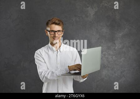 Portrait of happy young programmer, office worker, student or freelancer working on laptop. Stock Photo