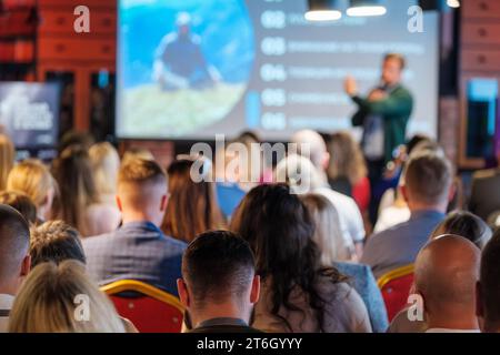 Back view of multiethnic business professionals listening to speaker giving presentation in conference hall Stock Photo