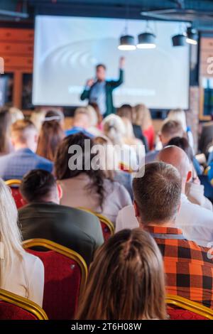 Back view of multiethnic business professionals listening to speaker giving presentation in conference hall Stock Photo