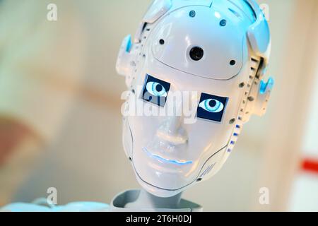 Closeup of white illuminated human robot looking camera against blurred background Stock Photo