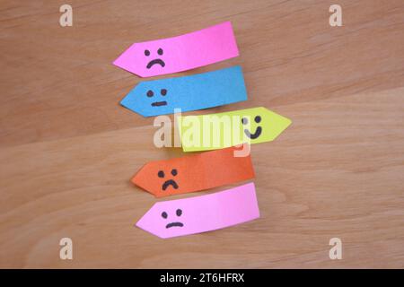 Positive Smiley Shines Among Sad Faces on Sticky Notes. Upholding Positivity Concept. Overcoming Sadness with Positivity. Stock Photo