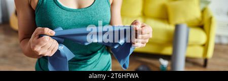 cropped view of young woman in sportswear holding resistance band in front of her, fitness, banner Stock Photo