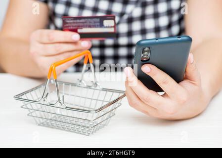 Womans hands hold credit card and use smartphone to shop online. Stock Photo