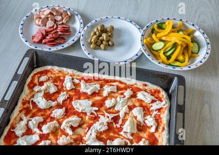 Homemade pizza preparation, pan, rolled out dough and garnish ingredients Stock Photo