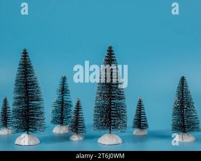 The photo shows several decorative artificial Christmas trees located on a bright blue background. The blue background creates a beautiful contrast an Stock Photo