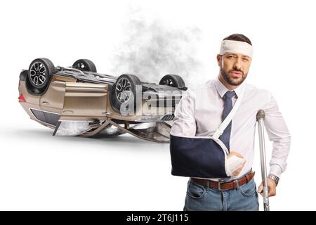 Injured driver after a car accident standing in front of a SUV turned upside down isolated on white background Stock Photo