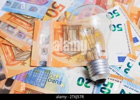 Light bulb on a pile of euro banknotes, electricity price increase concept Stock Photo