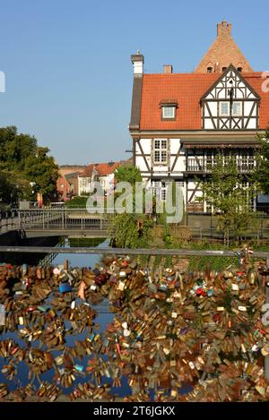 Love padlocks on the Bread Bridge or Bridge of Love and The House of the Millers' Guild in Gdansk, Poland Stock Photo