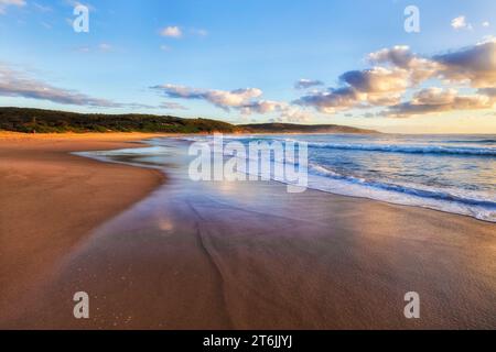 Flat sunlit Middle camp beach at Catherine hill bay town on Pacific coast of Australia at sunrise. Stock Photo