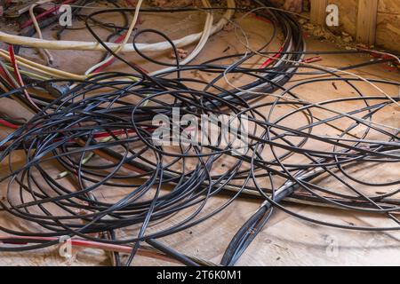 Cables and wiring on plywood floor inside abandoned commercial building. Stock Photo