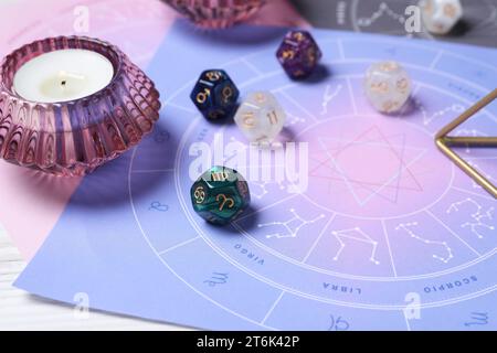 Zodiac wheel, astrology dices and burning candle on table, closeup Stock Photo