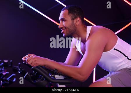 Young man training on exercise bike in fitness club Stock Photo