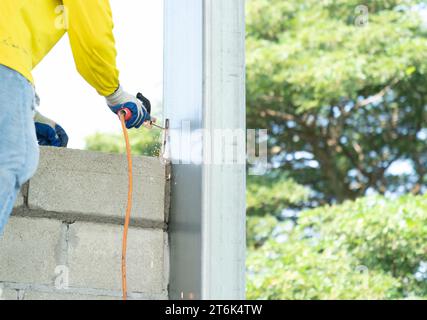 Construction workers welding rebar to steel pole columns to stabilize the masonry to increase the stability of the brick wall. Stock Photo