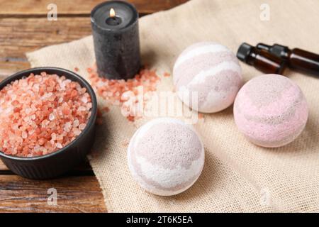 Bath bombs, sea salt, bottles of oils and burning candle on wooden table Stock Photo