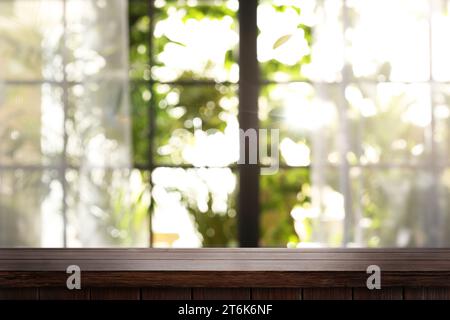 Empty wooden table against window in room, blurred interior. Space for design Stock Photo