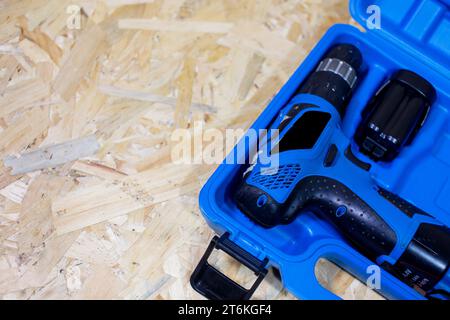 red electric drill lies in a dark suitcase on a wooden table Stock Photo