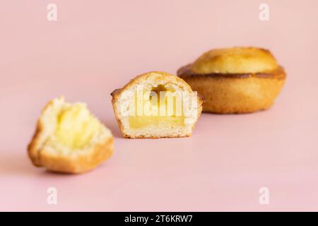 Pasticciotto leccese pastry filled with egg custard cream, typical sweet from Lecce, Italy. Half of baked pasticiotto on a pink, apulian breakfast, cl Stock Photo