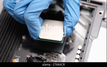 Technician examines microprocessor chip on PC motherboard Stock Photo