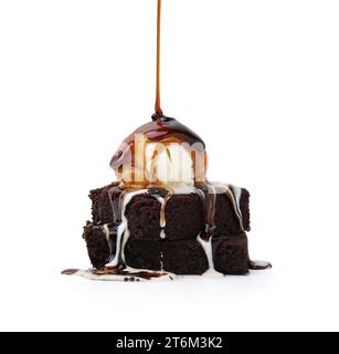 Pouring tasty caramel sauce onto ice cream and brownies isolated on white Stock Photo