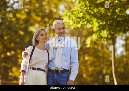Happy married elderly man and woman are walking together in green park in summer Stock Photo
