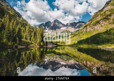 Majestic Mountain Peaks Surrounded by Trees and a Calm Lake Water Reflection at Maroon Bells, Colorado, USA Stock Photo
