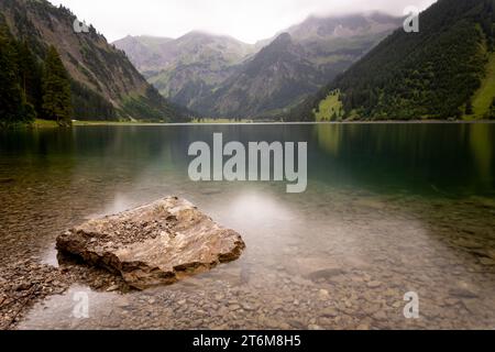 rock in mountain lake with crystal clear water, smooth surface and slightly blurred background in austrian alps vilsalpsee Stock Photo