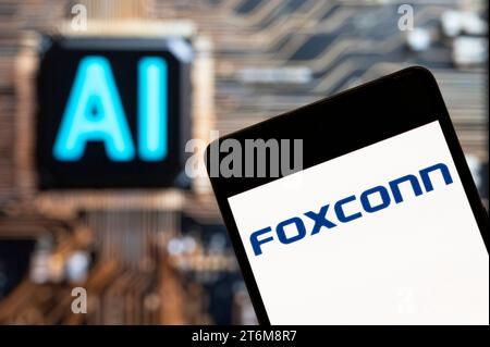 In this photo illustration, the world's largest contract maker of electronics, Foxconn, logo seen displayed on a smartphone with an Artificial intelligence (AI) chip and symbol in the background. Stock Photo