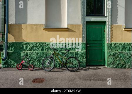 Two bicycles parked near the walls of a house with a green door. Saldus train station, Latvia. Stock Photo