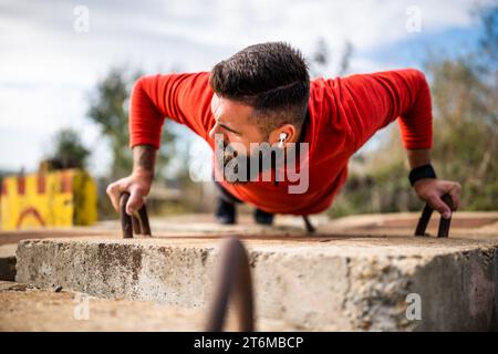 Young man is exercising outdoor. He is doing push-ups. Stock Photo