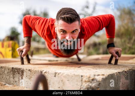 Young happy man is exercising outdoor. He is doing push-ups. Stock Photo