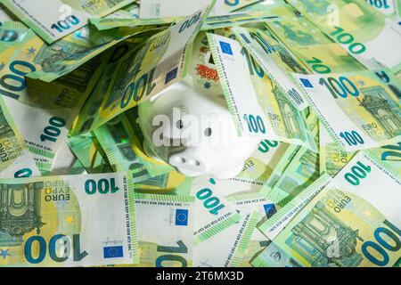 Money pig on the background of money bills of 100 euros covered with bills sticking out nose. High quality photo Stock Photo