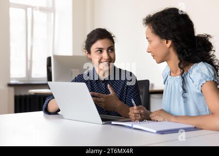 Happy young multiethnic businesswomen talking at laptop Stock Photo