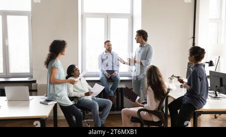 Diverse young business team employee speaking to group of colleagues Stock Photo